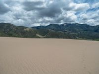 the sand field is very wide and empty in the open mountainside area, where the tracks of many people appear