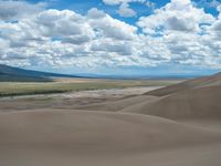 the view over the sand dunes in the desert, towards mountains and the wide expanse of water