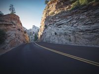 road with a rocky and canyon in the background while sun sets on the horizon in the evening