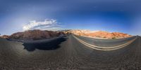 a long empty road going through the desert on an orange rock side, with a large sky