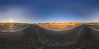 a wide angle lens of a wide open field covered with sand, with a desert in the background