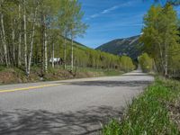 a yellow and black sign is on the street near some mountains and trees in the distance