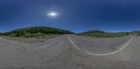 a 360 camera photograph of a empty mountain road and forest scene in motion with lens pointed slightly into the air