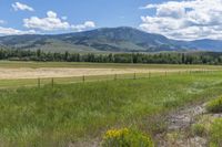 the landscape of an open country with tall mountains in the background and a wire fence