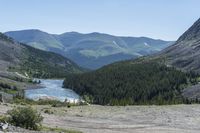 the mountains and trees are in front of a mountain lake with a man riding his motorbike