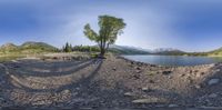 fisheye view of a small lake and mountains across a gravel road from the ground