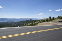 a car drives down the road in front of mountains and the sky is blue and clear