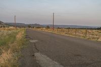 a empty road with no traffic and telephone poles near the side of it in an arid area