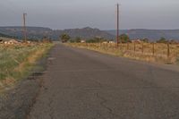 a empty road with no traffic and telephone poles near the side of it in an arid area