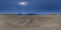 a 360 - view lens photo of a landscape with rocks and water in the distance