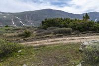 a person on a bike stands on a trail in the mountains with a view of a mountain range