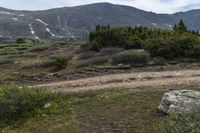 a person on a bike stands on a trail in the mountains with a view of a mountain range