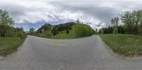 a person with a skateboard riding down the road in front of some hills and trees