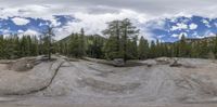 a view of a beautiful mountain range with clouds and pine trees as seen through a circular mirror lens