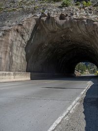 a road goes into a tunnel and through the hill to the other side of it