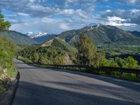 the road winds up on the mountainside on a sunny day with beautiful clouds and trees