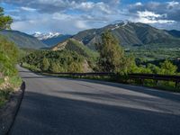 the road winds up on the mountainside on a sunny day with beautiful clouds and trees