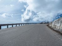 a snow covered road is near a very steep cliff on a clear day the wall is filled with snow and snow