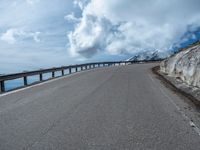 a snow covered road is near a very steep cliff on a clear day the wall is filled with snow and snow