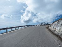 a snow covered road is near a very steep cliff on a clear day the wall is filled with snow and snow