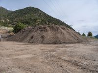 two yellow bulldozers work on sand and gravel in a mountain valley while another one looks at it