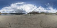 the landscape of a beach is distorted by a fisheye lens on an angle to see some sand and mountains