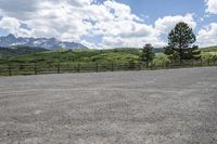 a person in an empty parking lot with a fenced area around them with mountains in the background