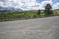 a person in an empty parking lot with a fenced area around them with mountains in the background