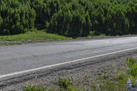 a small truck on a empty, deserted road in the country side with forest behind it