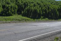 a small truck on a empty, deserted road in the country side with forest behind it