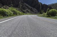 two lanes of asphalt road with white lines in middle and some rocks in the distance