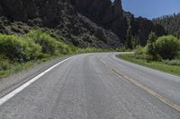 two lanes of asphalt road with white lines in middle and some rocks in the distance