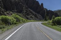 two lanes of asphalt road with white lines in middle and some rocks in the distance