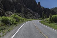 two lanes of asphalt road with white lines in middle and some rocks in the distance