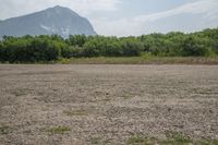 a dirt area with mountains in the background and trees in the foreground that's where the sand has been crushed by a large amount