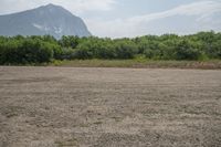 a dirt area with mountains in the background and trees in the foreground that's where the sand has been crushed by a large amount