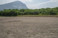 a dirt area with mountains in the background and trees in the foreground that's where the sand has been crushed by a large amount