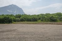 a dirt area with mountains in the background and trees in the foreground that's where the sand has been crushed by a large amount