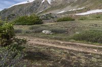 a group of people riding bicycles down a dirt trail in the mountains during daytime time