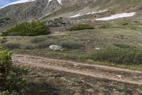 a group of people riding bicycles down a dirt trail in the mountains during daytime time