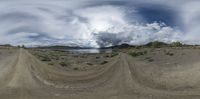 a distorted picture of an empty road near a lake and hills with clouds above the mountains