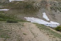 two horses with bags sitting on top of them in the mountains by water and snow