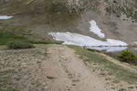 two horses with bags sitting on top of them in the mountains by water and snow