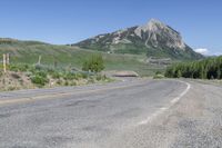 a view of a large mountain in the background with a road with white lines and yellow stripes