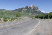 a view of a large mountain in the background with a road with white lines and yellow stripes