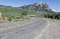 a view of a large mountain in the background with a road with white lines and yellow stripes