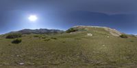 an unusual view of the mountains and sky and grass in the field as seen through a fish - eye lens