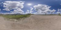 this view is of an empty road with dirt roads in the distance and clouds above