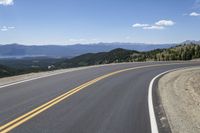 a road with mountains and yellow lines running on it, with a bicycle leaning up against it