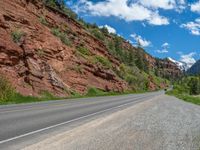 the red rocks are high up on the side of the road and it is an amazing color